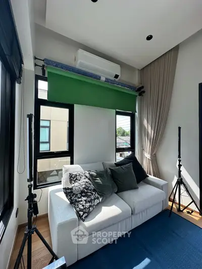 Modern living room with cozy sofa and large windows, featuring stylish decor and natural light.