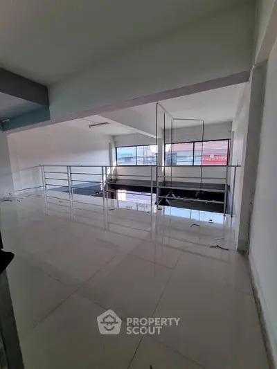 Spacious modern interior with sleek railing and large windows offering ample natural light.