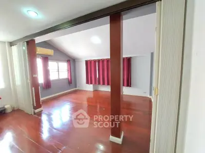 Spacious room with wooden flooring and large windows in a modern home.