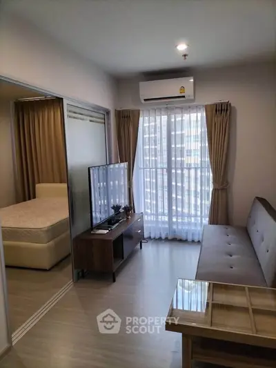 Modern living room with natural light, sleek furniture, and a glimpse of a cozy bedroom.