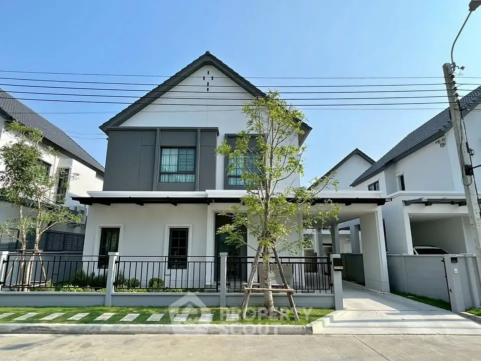 Modern two-story house with sleek design and spacious driveway in a serene neighborhood.