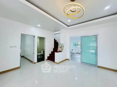 Spacious modern living room with elegant lighting and glossy flooring, featuring a staircase and sliding glass door.