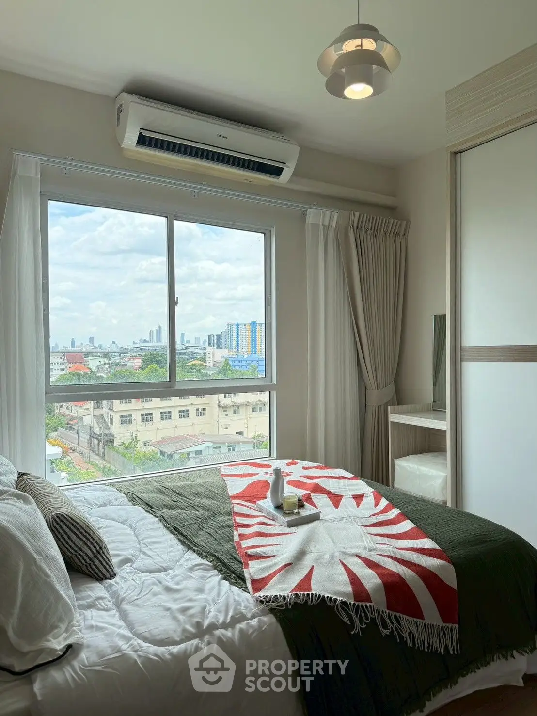 Cozy bedroom with city view, featuring stylish decor and natural light.