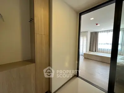 Modern bedroom with wooden flooring and ample natural light, featuring a sliding door and built-in storage.