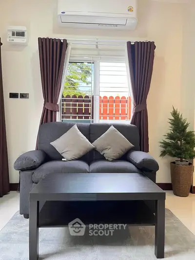 Cozy living room with modern sofa, coffee table, and air conditioning, perfect for relaxation.