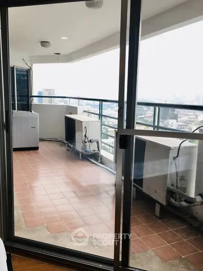 Spacious balcony with city view and air conditioning units in high-rise apartment.