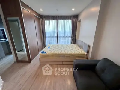 Modern bedroom with large window and wooden flooring in a stylish apartment.