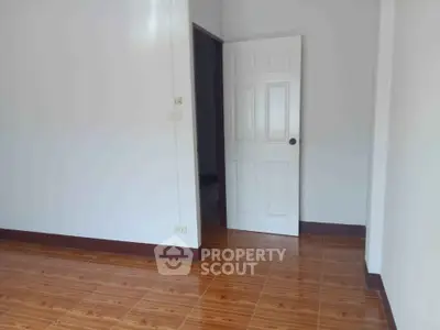 Spacious empty room with wooden flooring and white walls, perfect for customization.