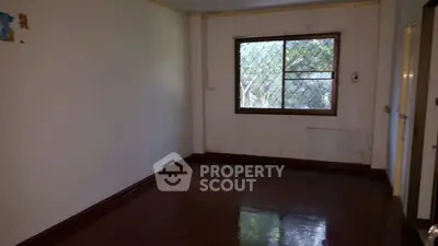 Spacious empty room with large window and wooden flooring, ideal for customization.