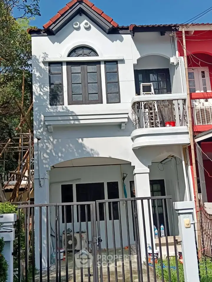 Charming two-story townhouse with balcony and gated entrance in a vibrant neighborhood.