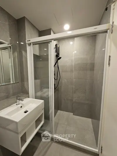 Modern bathroom with sleek shower and stylish sink in contemporary apartment.