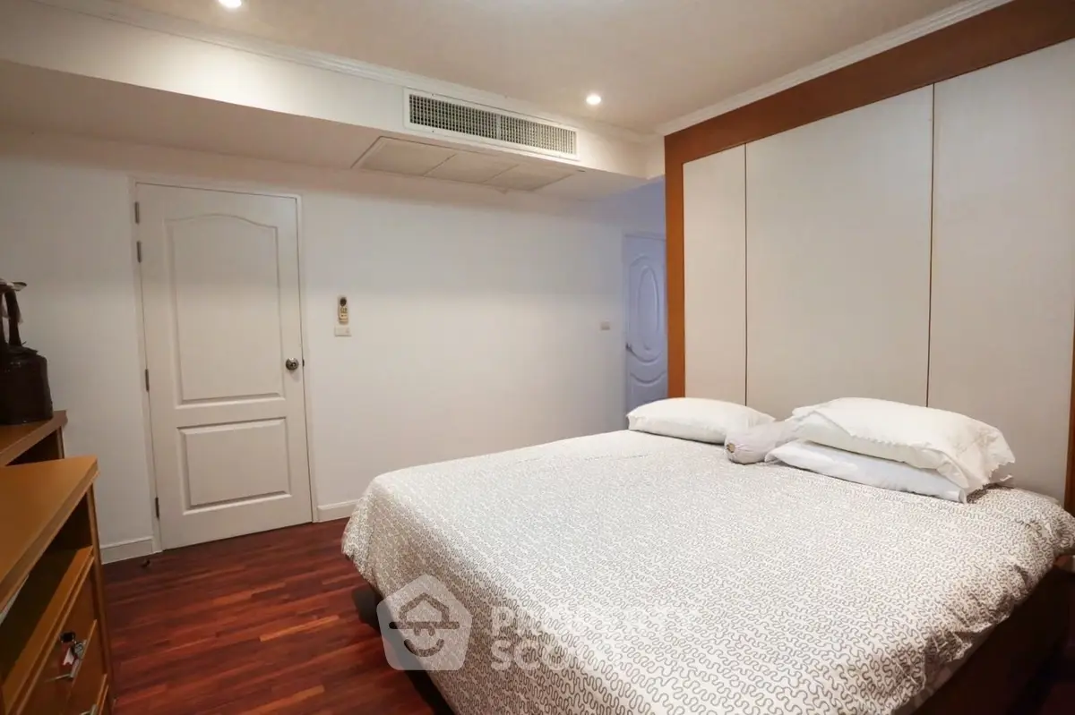 Cozy bedroom with modern design and wooden flooring, featuring a comfortable bed and ample storage space.