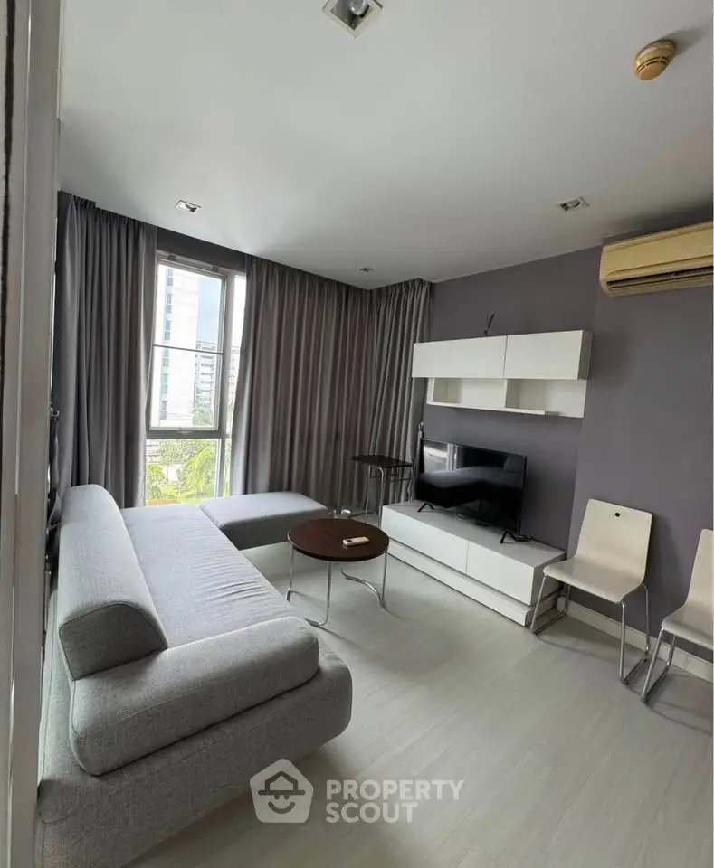 Modern living room with sleek furniture and large window offering city view