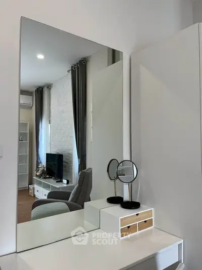 Modern living room with stylish decor and large mirror reflecting cozy seating area.