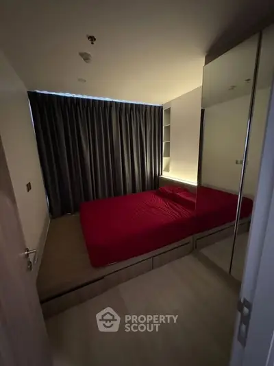 Cozy modern bedroom with red bedding and mirrored wardrobe