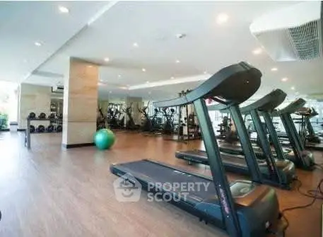 Spacious modern gym with state-of-the-art equipment and large mirrors in a luxury residential building.