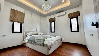 Elegant bedroom with modern chandelier and cozy bedding in a stylish home.