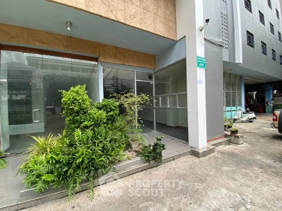 Modern building entrance with glass doors and lush greenery, ideal for commercial or residential use.