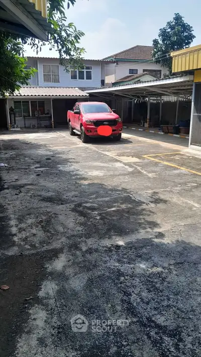 Spacious residential parking area with covered spots and a red SUV parked, ideal for urban living.