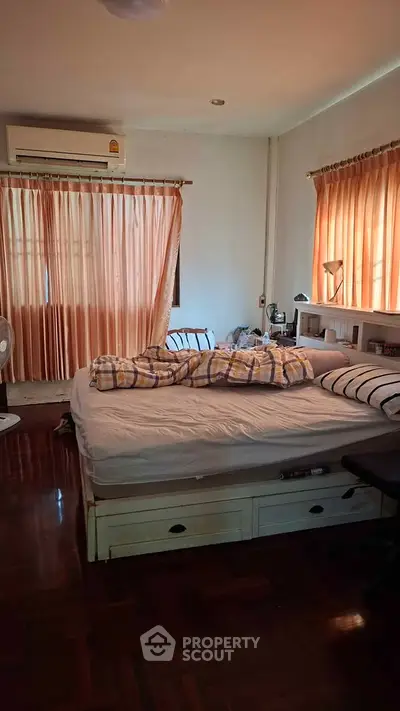 Cozy bedroom with natural light, featuring a comfortable bed and elegant curtains, perfect for relaxation.
