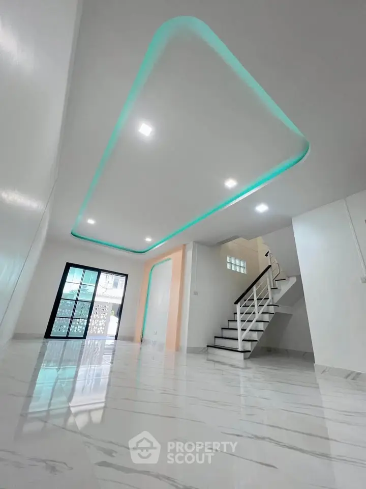 Modern interior with sleek staircase and stylish ceiling lighting in a spacious living area.