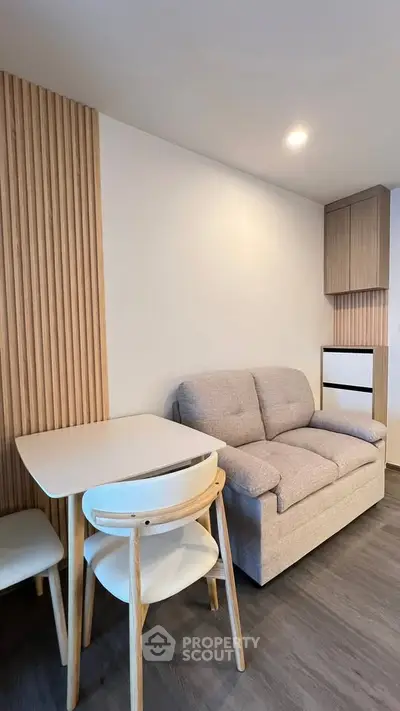 Modern living room with cozy sofa and dining table, featuring stylish wooden accents and soft lighting.