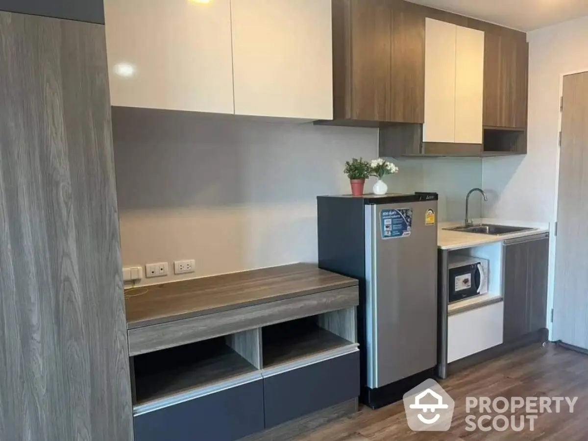 Modern kitchen with sleek cabinetry and compact fridge in stylish apartment