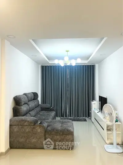 Modern living room with plush gray sofa and sleek entertainment unit.