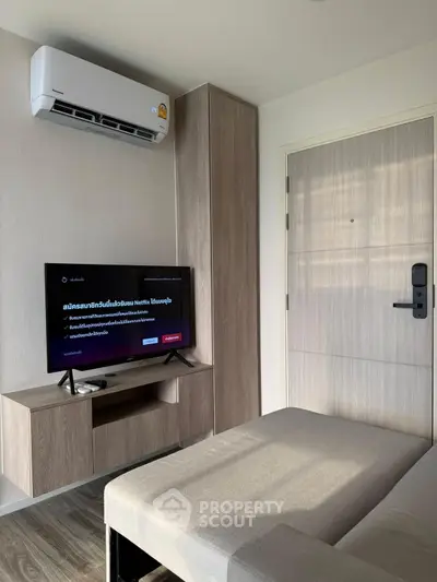 Modern living room with sleek furniture and wall-mounted TV, featuring air conditioning.