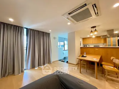Modern open-plan living room with dining area and kitchen, featuring stylish lighting and wooden flooring.
