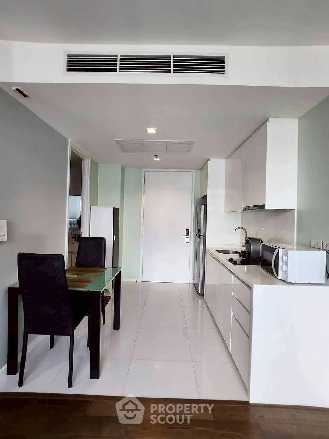 Modern kitchen with sleek white cabinetry and dining area in a stylish apartment.