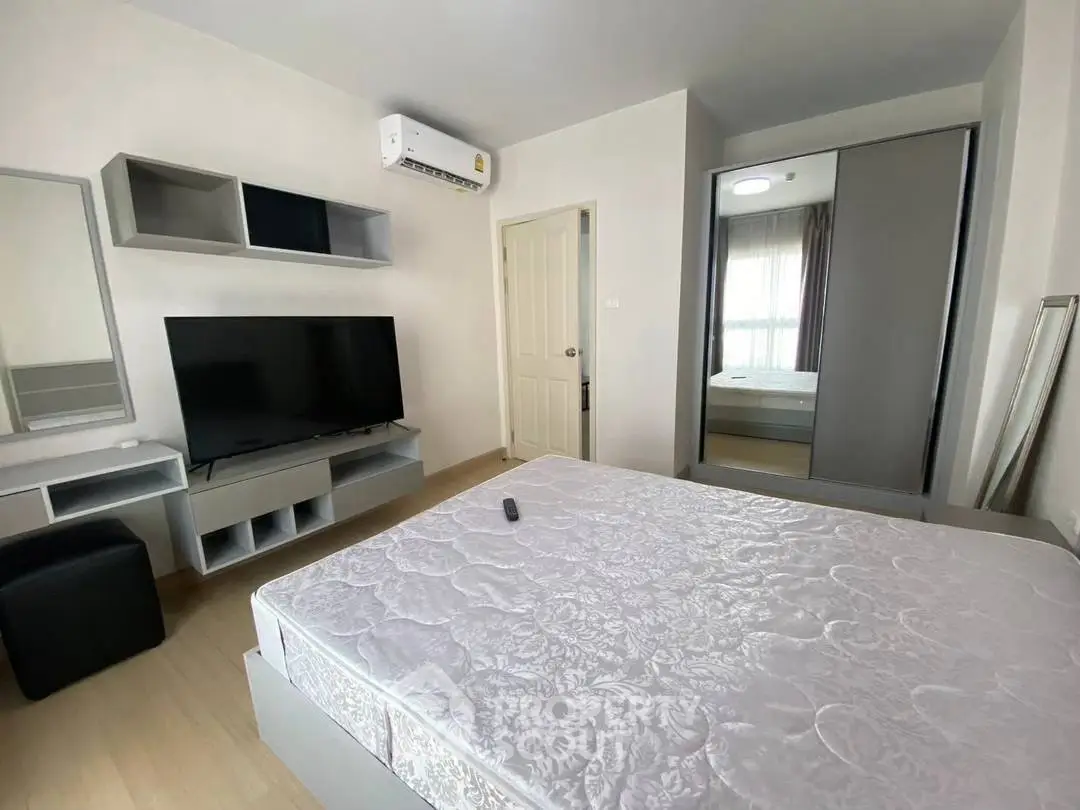Modern bedroom with large TV and air conditioning, featuring a comfortable bed and sleek storage solutions.