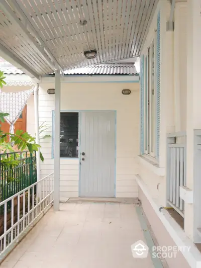 Charming exterior view of a cozy home entrance with covered porch and garden.