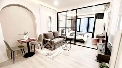 Modern open-plan living room with stylish decor and bedroom view in a chic apartment.