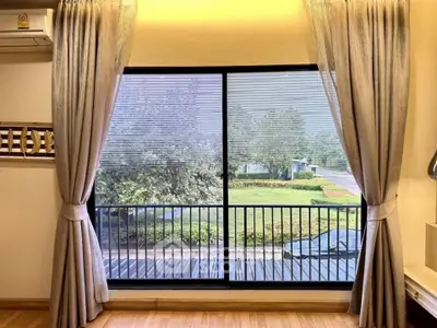 Spacious room with large window offering serene garden view, perfect for relaxation.