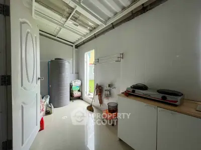 Compact kitchen with dual hot plate and storage, featuring a water tank and garden view.