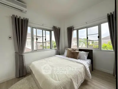 Bright bedroom with large windows and modern decor in a cozy home setting.