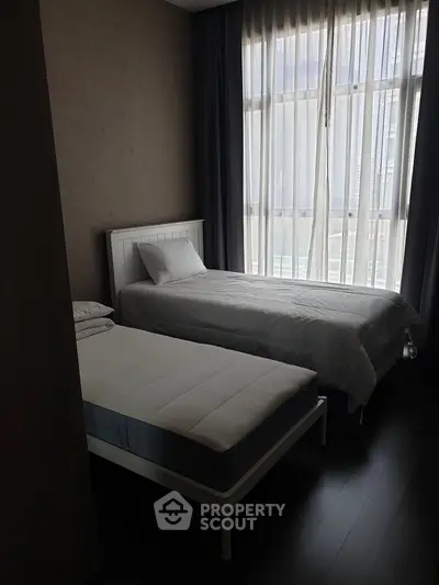 Cozy bedroom with two single beds and large window offering natural light.