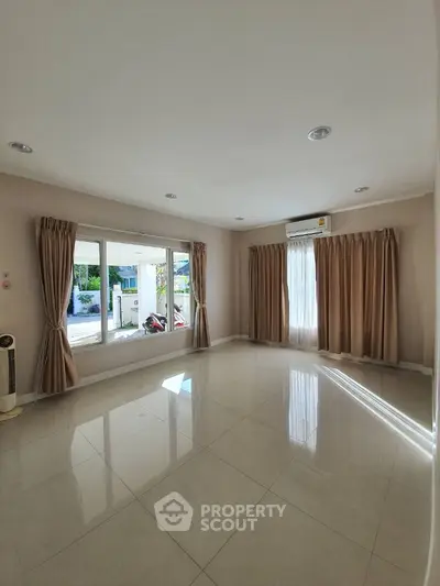 Spacious living room with large windows and tiled floor, perfect for natural light and modern living.