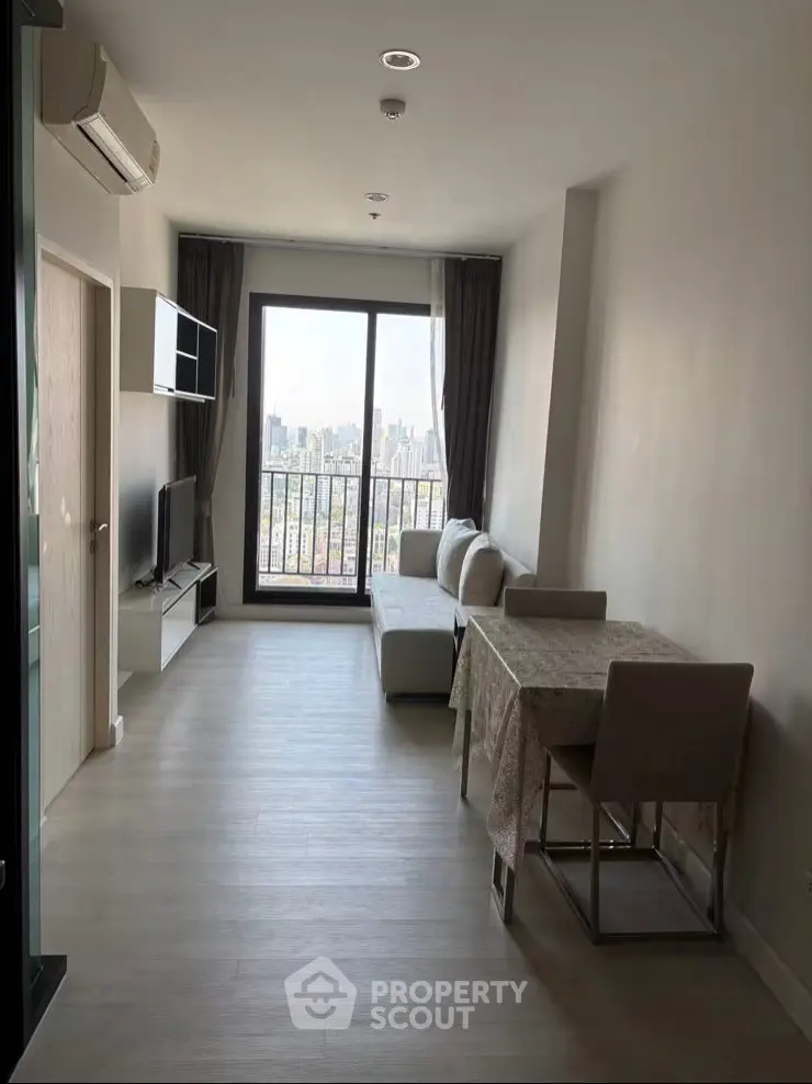 Modern living room with city view, featuring sleek furniture and large windows for natural light.