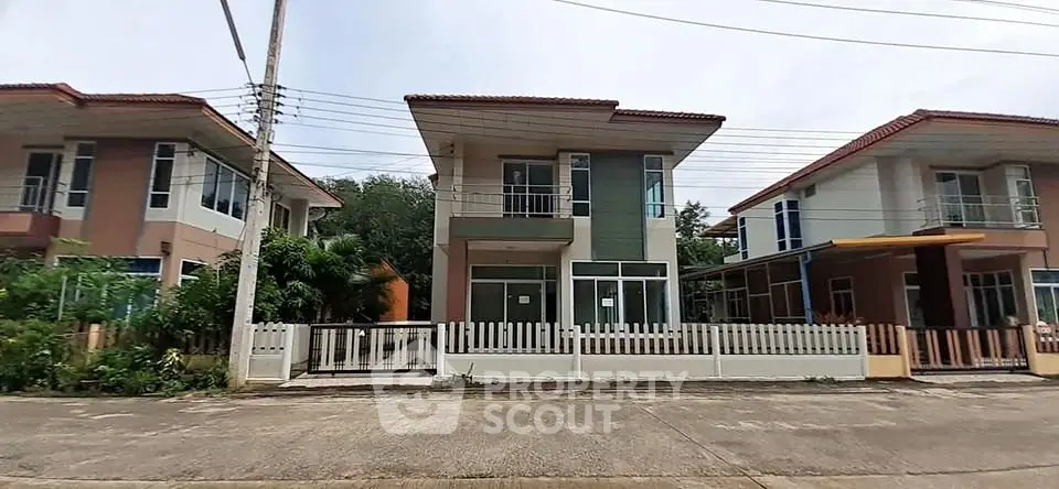 Modern two-story house with balcony and fenced yard in suburban neighborhood.