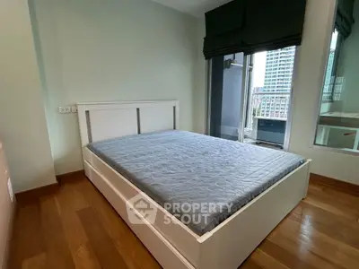 Modern bedroom with wooden flooring and balcony access in urban apartment