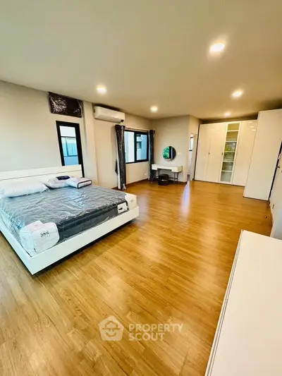 Spacious modern bedroom with wooden flooring and stylish furnishings