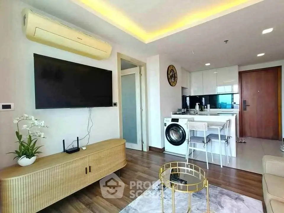 Modern living room with open kitchen, featuring a washing machine and stylish decor.