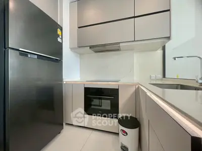 Modern kitchen with sleek cabinetry and built-in appliances, featuring a black fridge and minimalist design.
