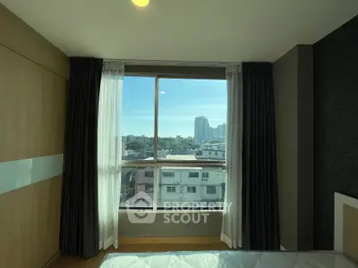 Bright bedroom with large window offering stunning city view in modern apartment.