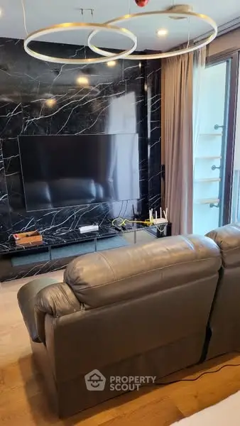 Luxurious living room with modern decor and large TV, featuring elegant black marble wall.