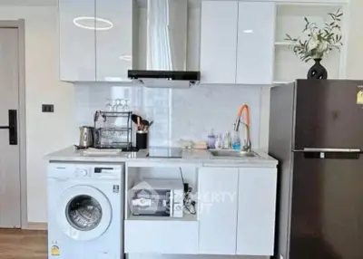 Modern kitchen with washing machine, oven, and sleek cabinetry in compact layout.