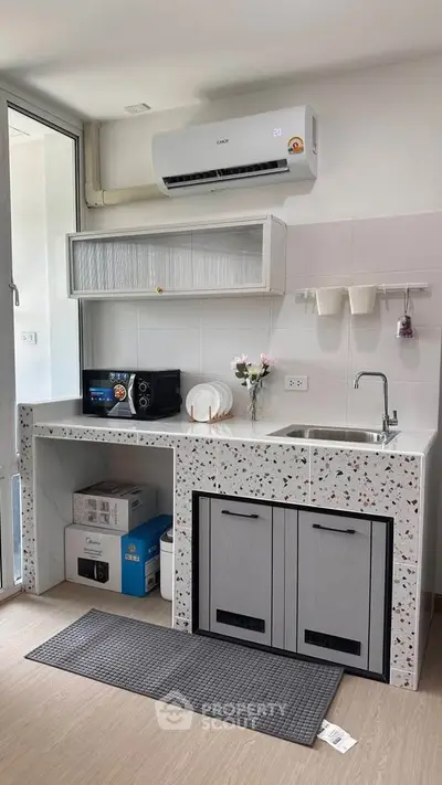 Modern kitchen with terrazzo countertops, air conditioning, and sleek cabinetry in a bright, airy space.