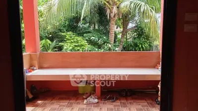 Charming tropical balcony with lush greenery and cozy seating area, perfect for relaxation.